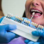 Dentist examining female patient with teeth shades at dental clinic
