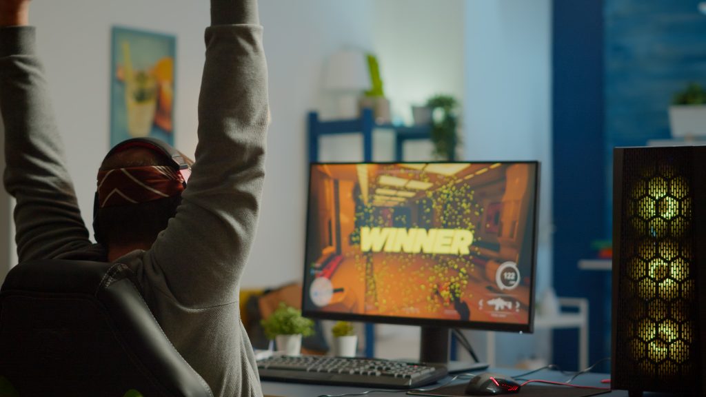 Back shot of happy man gamer wining first person shooter video game
