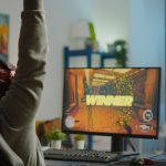 Back shot of happy man gamer wining first person shooter video game
