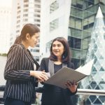 Businesswomen discussing over paperwork together against railing