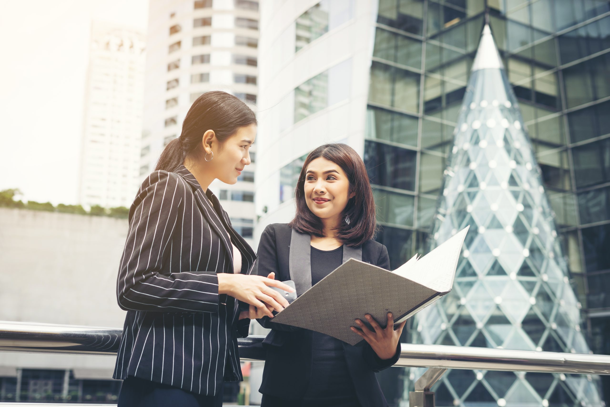 Businesswomen discussing over paperwork together against railing